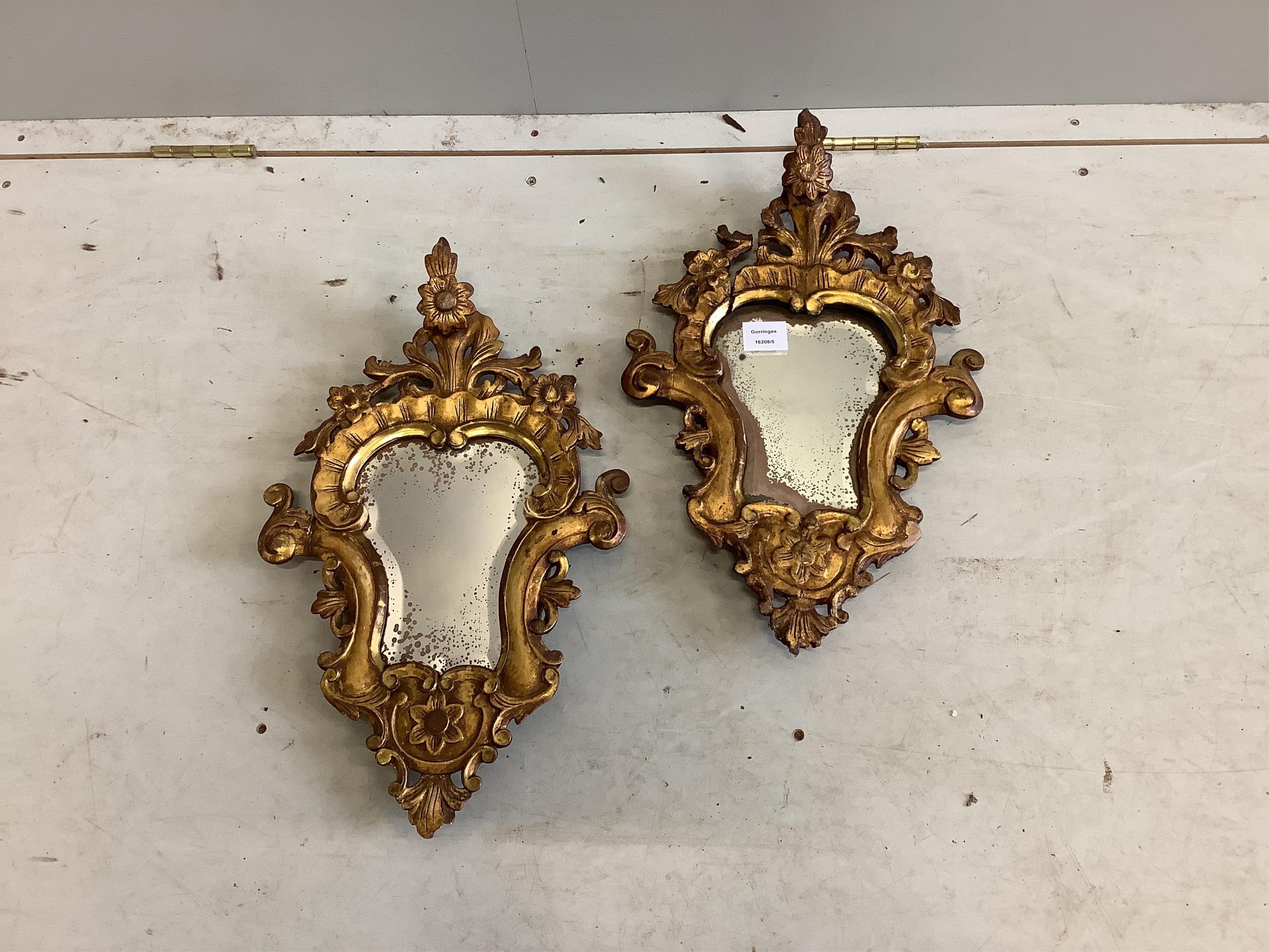 A pair of cartouche shaped carved giltwood wall mirrors, width 31cm, height 51cm. Condition - poor to fair